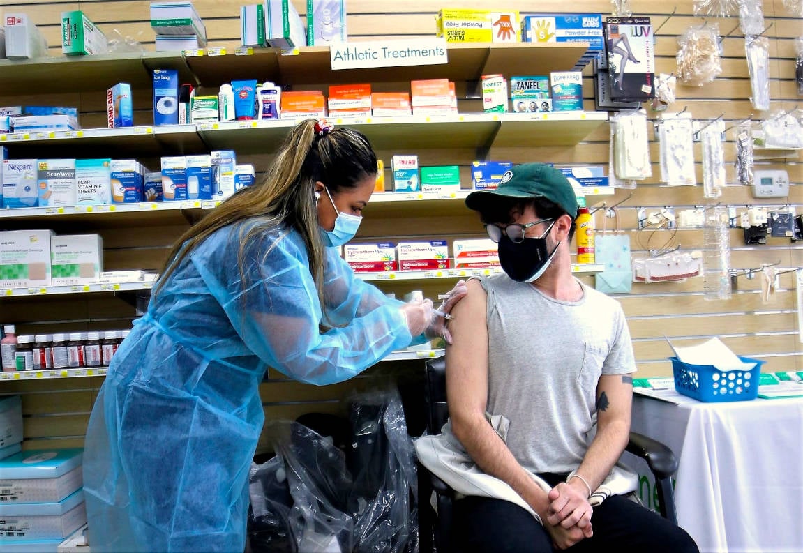 pharmacist vaccinating patient inside pharmacy - v 3